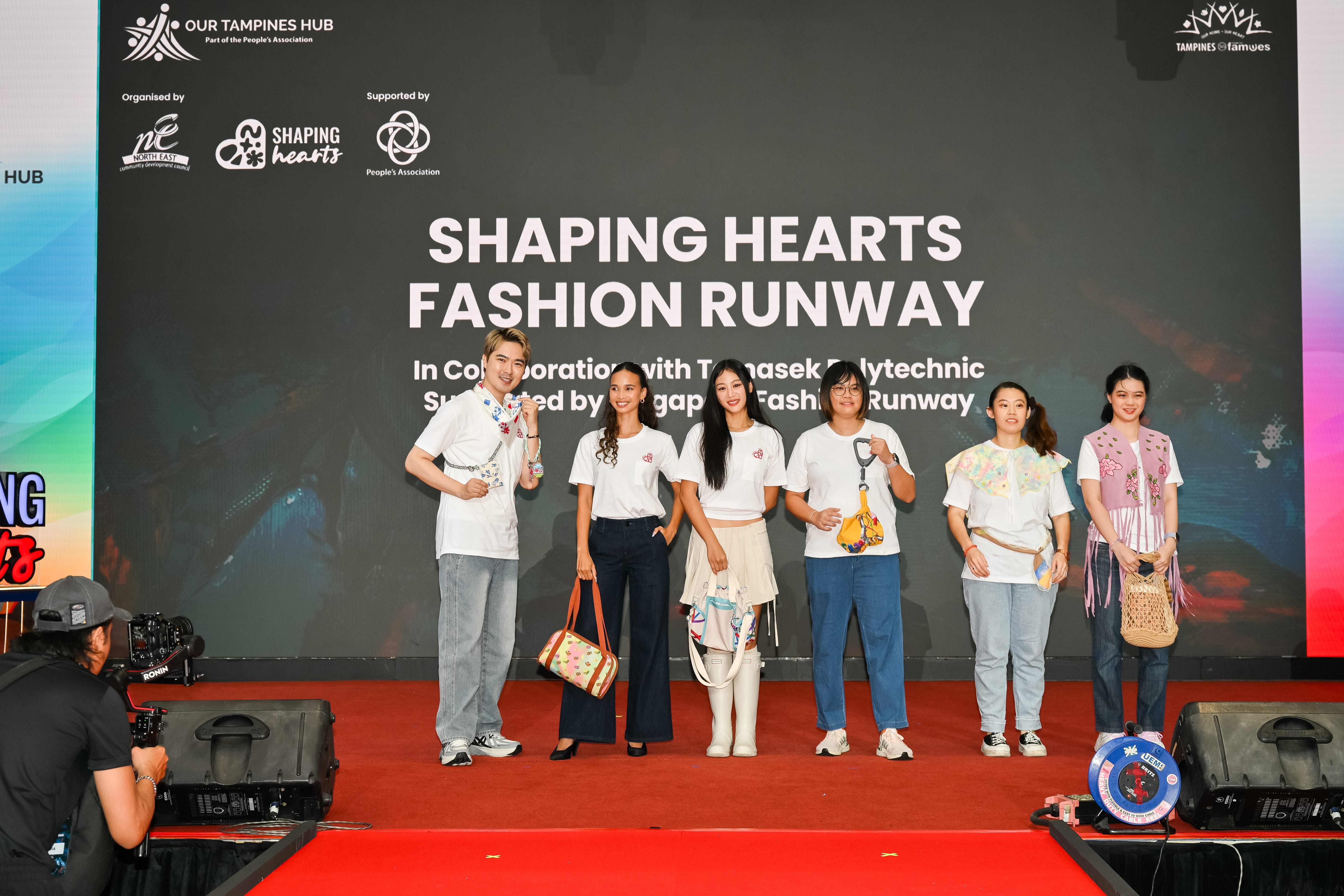 Participants posing on stage during the Shaping Hearts Fashion Runway, showcasing creative fashion pieces as part of an inclusive arts festival.